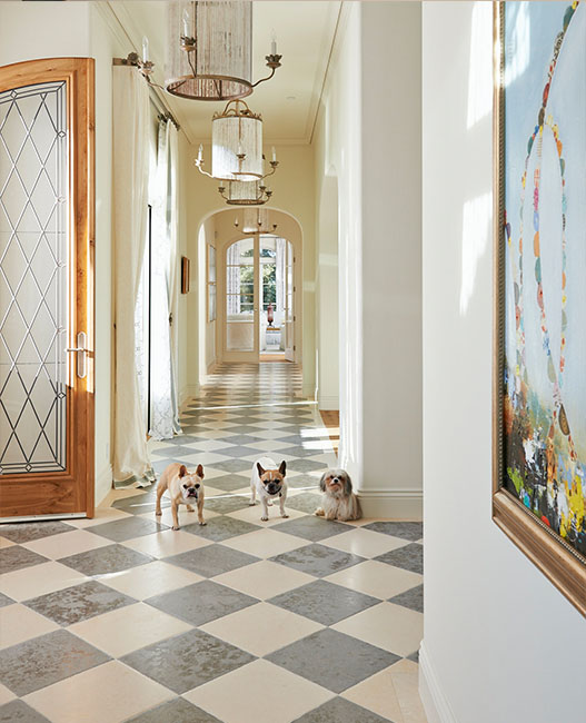Three dogs standing in a lavish hallway with marble tile